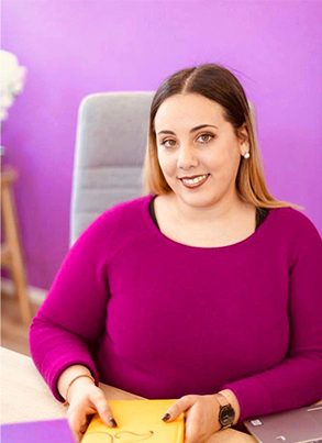 Portrait von Andrea Fernandes, Geschäftsinhaberin Prime Consulting GmbH, vor magentafarbener Wand.